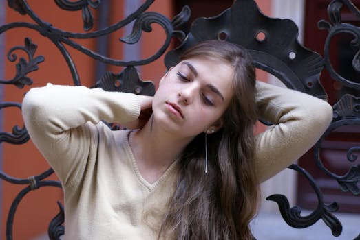 Young woman with closed eyes leaning against intricate black ironwork, creating a serene mood.